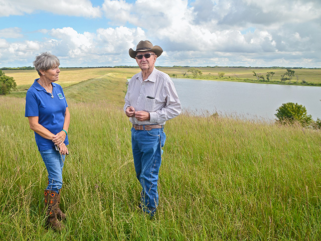 Former NRCS water-quality coordinator Denise Middleton and Larry Womack discuss lush native prairie grasses that grace Womackâ€™s operation on a hill overlooking the areaâ€™s last upstream flood-control project. Womack says the lake covered 46 acres of cropland but now protects hundreds of acres downstream, Image by Dan Crummett